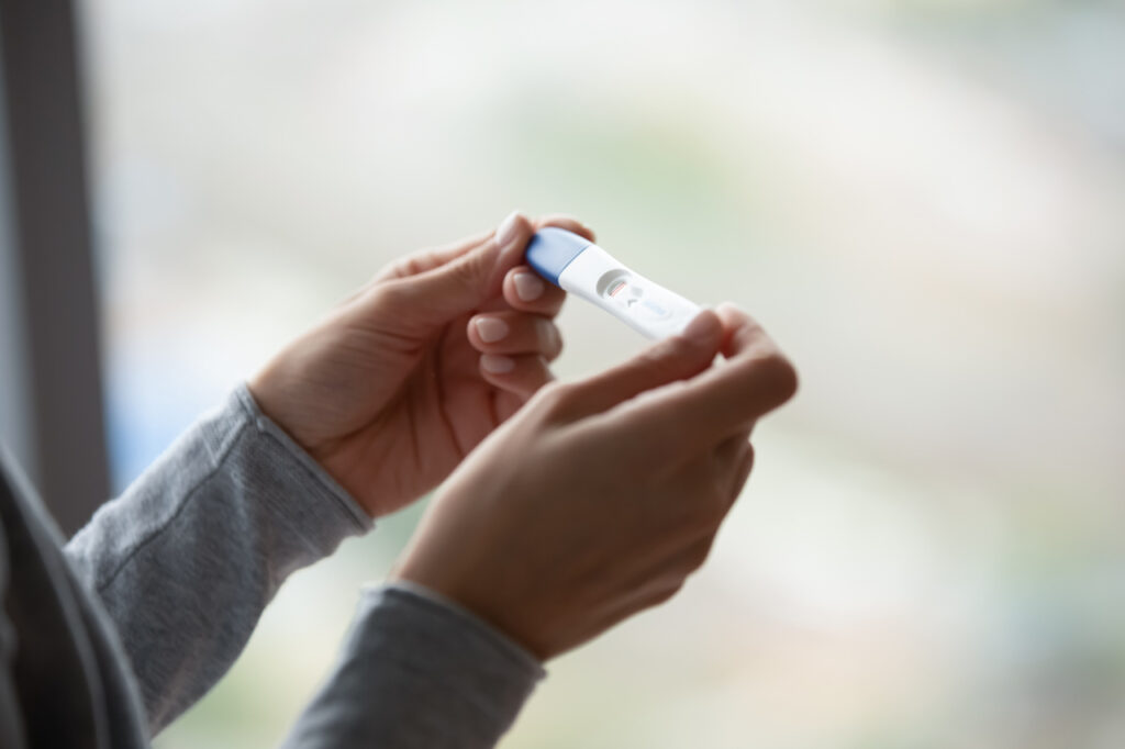 Two bars. Close up of woman hands holding positive home pregnancy test, confused female meeting unexpected gestation thinking making difficult choice, happy lady receiving news of awaited maternity